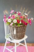 Large basket of cosmos, zinnias and fountain grass on white chair with china feather-shaped pendant