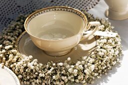 Nostalgic, gold-rimmed teacup festively decorated with wreath of gypsophila