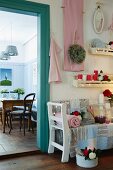 Romantically decorated sales room with fairy lights and country-house-style home accessories; view into cafe with nostalgic furnishings