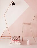 Standard lamp with copper tube frame, bar stool and cushion with geometric patterns in front of wall in shades of pink