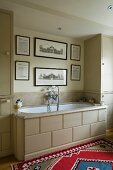 Englisches Bad in Beigetönen mit historischer Bildergalerie und buntem Orientteppich vor einer Einbauwanne