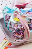 Colourful confetti in jars decorated with ribbons