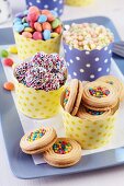 Polka-dot paper muffin cases of colourful biscuits, Smarties and puffed rice on tray