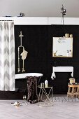 Black bathroom - metal side table, black glossy bathtub with shower head and mirror above sink against black wall