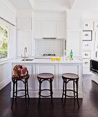 Thonet bar stools and white island counter in open-plan, country-house-style kitchen area