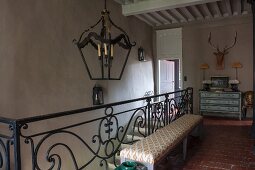 Wrought iron balustrade of staircase with bench and pendant lamp on landing