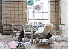 Listed industrial interior used as party location with delicate, romantic furnishings and decorated with balloons and paper pompoms