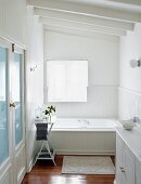 Elegant country-house-style, white bathroom with wood-clad bathtub and half-height wood panelling