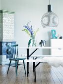 Scandinavian, designer pendant lamp above white, folding table and benches and black kitchen chair in front of tiled stove