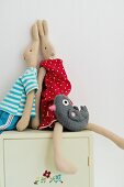 Rabbit soft toys dressed in clothes on cabinet
