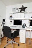 White home office with dark grey swivel chair, camera on tripod and black star ornament