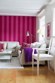 Seating area in Scandinavian living room with white furniture against red and pink striped wallpaper