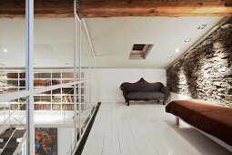Galerie unter dem Dach mit Ruhebank vor Natursteinwand und weiss lackiertem Dielenboden in renoviertem Landhaus