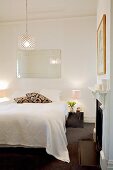 Doppelbett mit weisser Tagesdecke in klassischem Schlafzimmer mit offenem Kamin