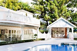 weiße Villa im Kolonialstil und Gartenhäuschen mit möblierter Terrasse um Pool in tropischem Umfeld