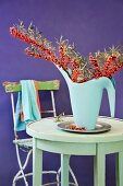 Arrangement of sea buckthorn branches in watering can on table