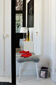 Stool with grey furry cover in front of mirror on wall