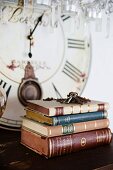 Antiquarischer Bücherstapel und Schlüsselbund auf Ablage, im Hintergrund altes Ziffernblatt einer Uhr