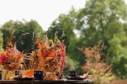 Strohbündel mit Blüten dekoriert auf Tisch