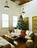 Rattan Sofagarnitur mit weissen Sitzpolstern unter Art Deko Pendelleuchten und geschmückter Weihnachtsbaum in ländlichem Wohnzimmer