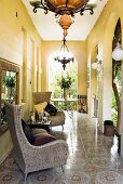 Yellow-painted veranda with arches, comfortable wicker armchairs and ornamental floor tiles