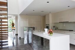 Offene Designer Einbauküche mit Küchentheke in Weiß und hochglänzender Steinboden in modernem Wohnhaus