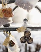 Kleine Tüten mit Plätzchen hängen als Adventskalender am verschneiten Zaun