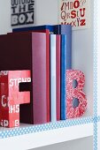 Colourful alphabet bookends on white bookshelf