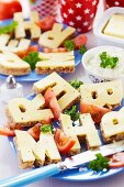 Buffet of bread and cheese cut into alphabet shapes on plates
