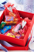 Chocolate bars with alphabet wrappers in small organza bags in red gift box