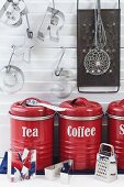 Arrangement of red tea and coffee storage jars, letter-shaped pastry cutters and grater in kitchen