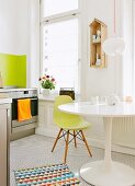 Mixture of classic furnishings in kitchen - white tulip table and green shell chair in white kitchen