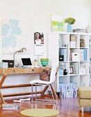 Chair with white upholstery in front of wooden desk next to white shelves of office supplies