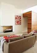 Back of sofa with view of fireplace and wooden wall element; red and white painting and scatter cushions