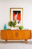 Modern painting above arrangement of vases and green bowl on 70s sideboard
