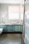 Blick in minimalistisches Bad auf Waschtisch mit satinierten Glastüren vor Fenster