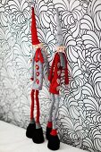Figurines wearing gnomes' hats leaning against wall with floral wallpaper