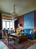 Antique armchairs with modern upholstery and blue sofa set around coffee table in grand interior with modern ambiance
