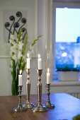 Lit candles in silver candlesticks on table