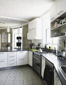 Umlaufende Küchenzeile in moderner Küche mit weissen Schränken und gefliestem Boden