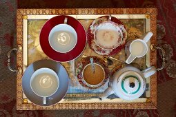 Top view of antique tray holding contemporary and traditional teacups and saucers