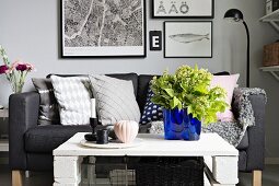 White and grey seating area with sofa, DIY coffee table, bright blue glass vase as focal point and gallery of pictures in background