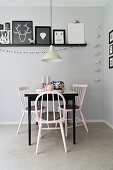 Black and white dining area with vintage chairs and colour-coordinated gallery of pictures on grey-painted wall
