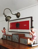 Stereo system below framed picture and vintage wall lamp in white, wood-clad wall