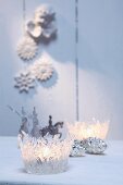 Zwei weihnachtliche Windlichter aus geformten, transparenten Heisskleberfäden