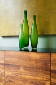 Set of three green vases on sideboard with walnut front