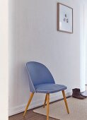 Blue, fifties chair against white wall in simple, white hallway