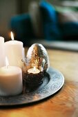White, lit candles and tealight holder on pewter tray