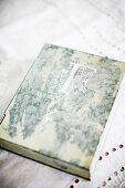Antiquarian book with initial on cover on white lace tablecloth