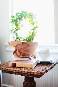 Ivy topiary ring, book and teacups on wicker side table